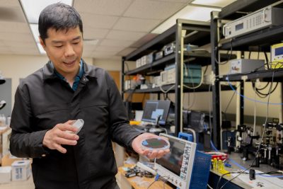 Associate Professor Wei Zhou holds up biochips in part of his Multi-Modal Lab in Whittemore Hall. 
